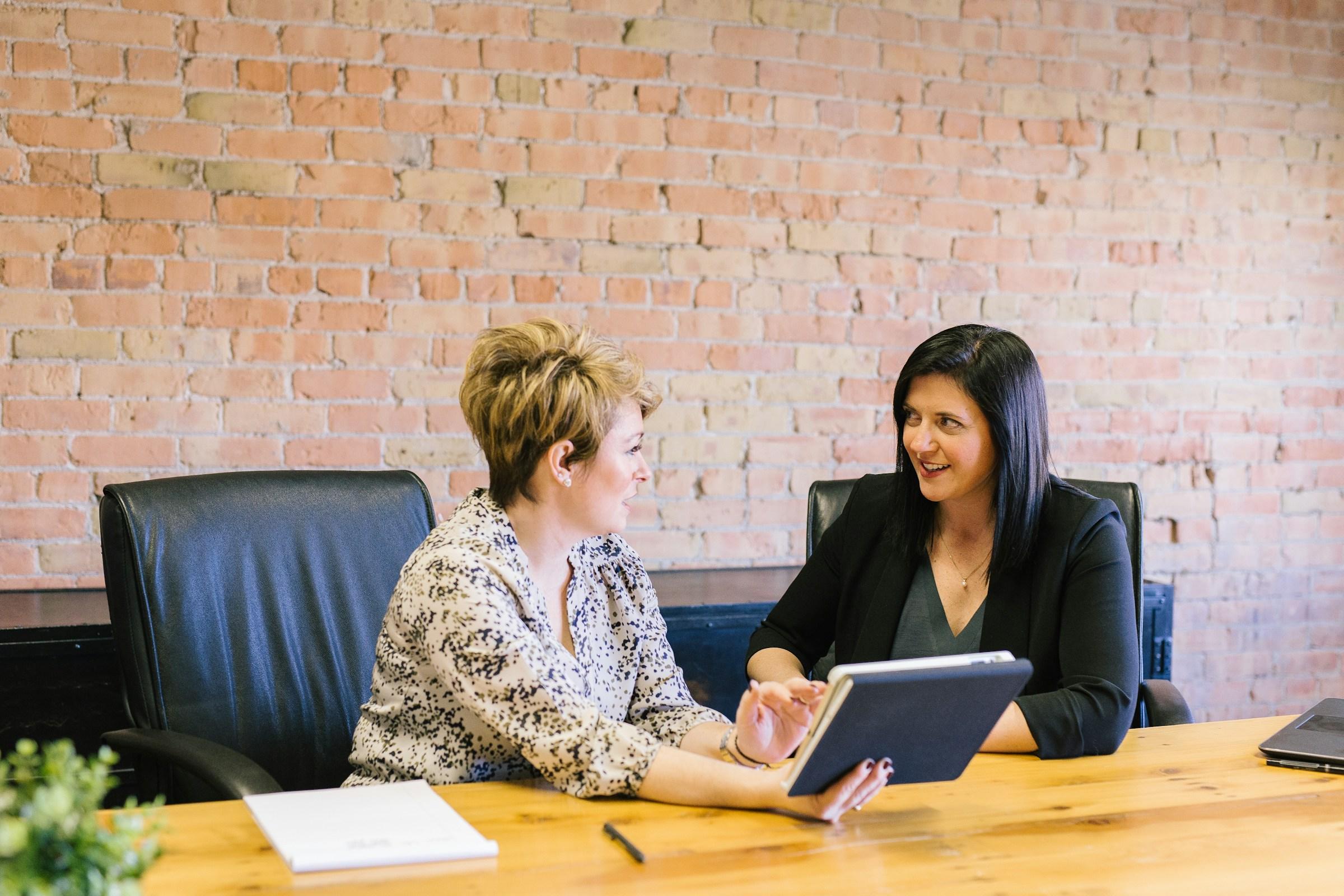 amy-hirschi-K0c8ko3e6AA-unsplash Two women sitting on leather chairs in front of table